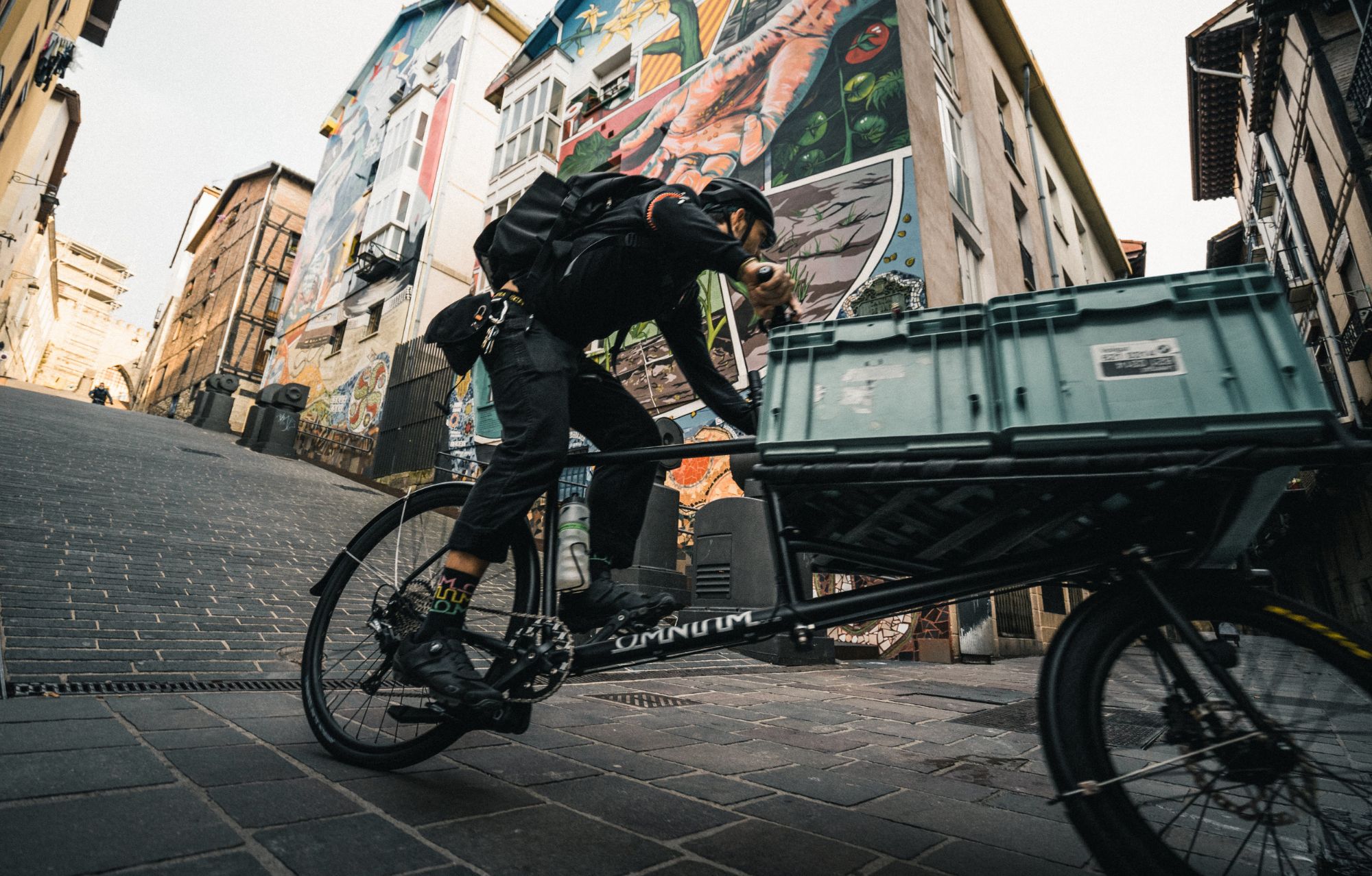 Un repartidor sube una cuesta del Casco Viejo con la caja de la bici llena