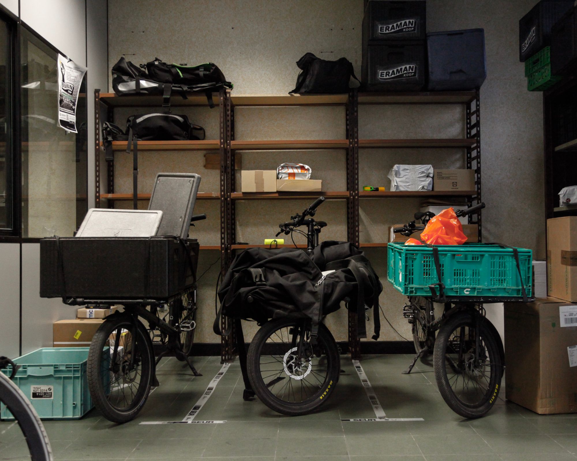 Tres bicis de carga aparcadas en el hub, delante de las estanterías